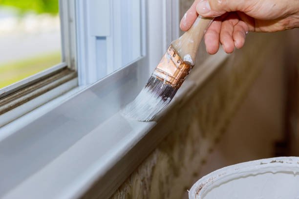 Close up of a man hand carefully painting the edge of an house window